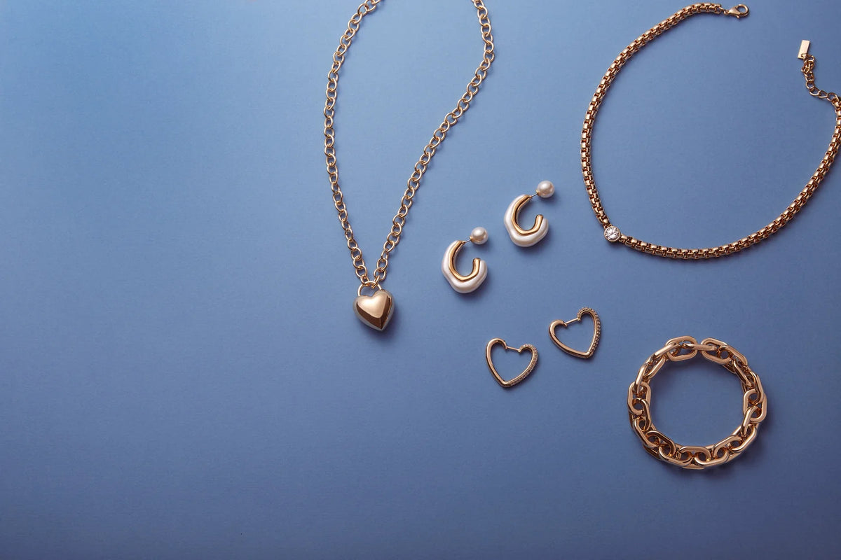 Goldfarbene Halsketten, Ohrringe und Armbänder auf blauem Hintergrund.