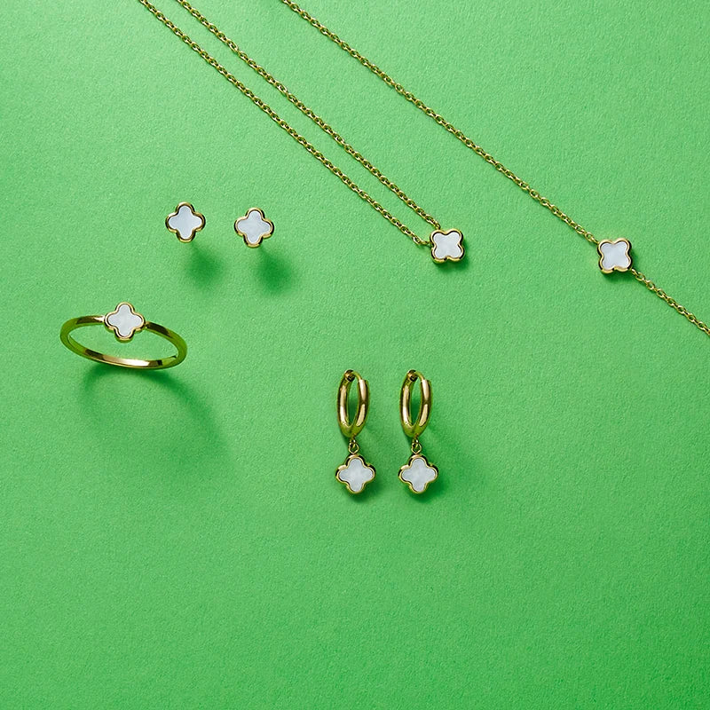 Schmuck mit Kleeblattmotiven auf grünem Hintergrund.